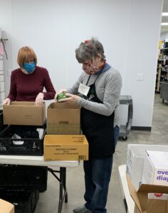 Suzan Perry volunteers during her shift at the Durham Community Food Pantry placing a vegetable into a box.