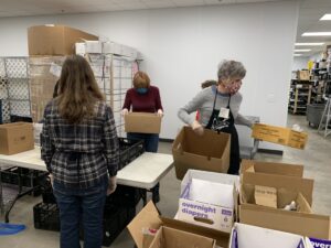 Volunteers pack food into boxes.